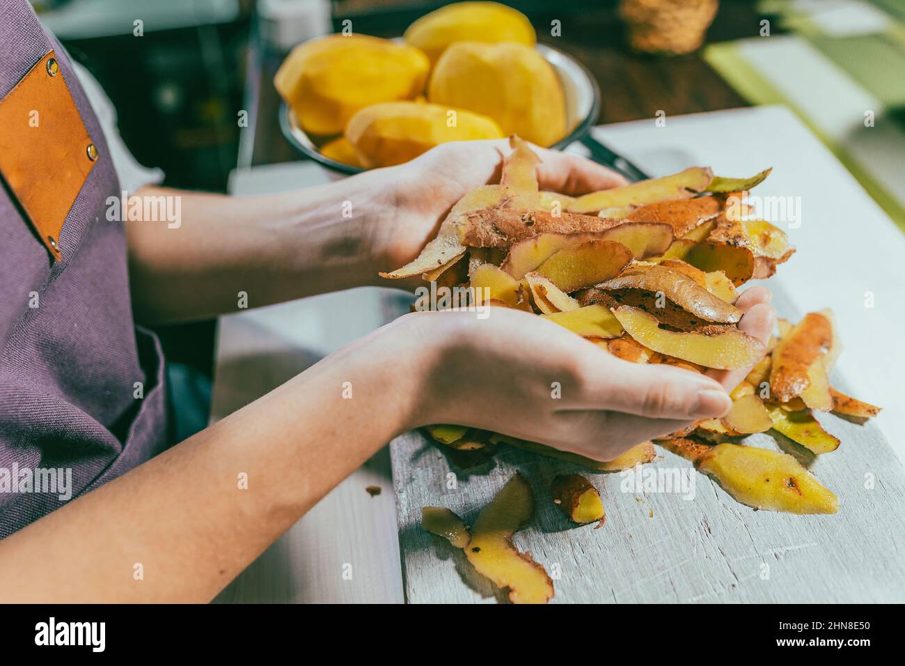 Potato peelings in hands of female cook. Use and processing of food waste, composting, in order to enrich soil fertility. Garbage sorting at home Stock Photo