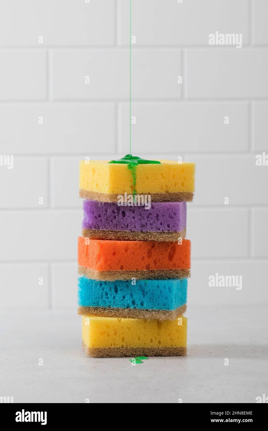 Sponges for washing dishes are stacked, green dishwashing gel pours