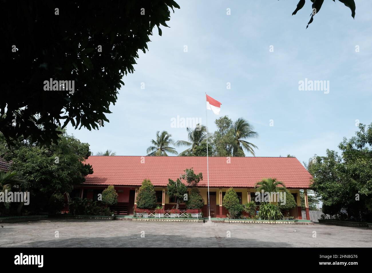 Indonesian flag fluttering in the school yard against the blue sky background Stock Photo