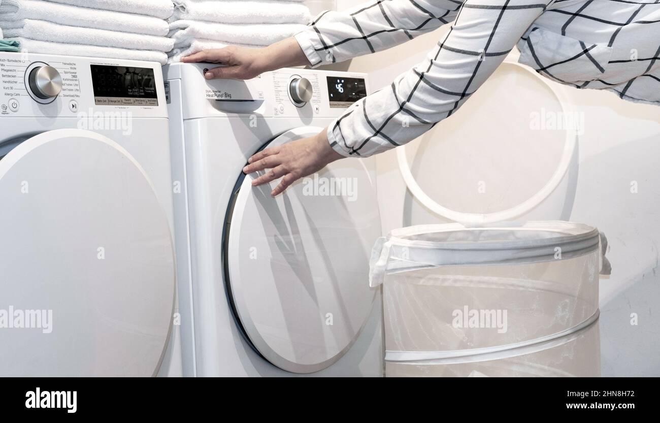 Female hands hold towels near wash and dry machines in the laundry