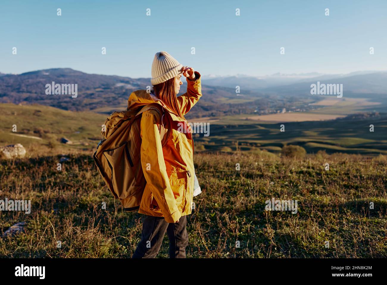 woman in a yellow jacket in a hat backpack travel mountains Fresh air