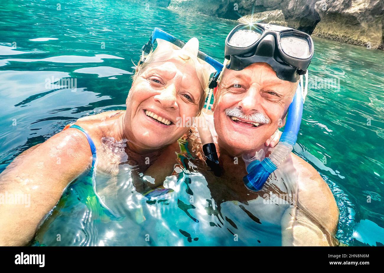 Happy retired couple with scuba mask taking selfie at tropical excursion - Boat trip snorkel experience in exotic scenarios - Elderly concept with act Stock Photo