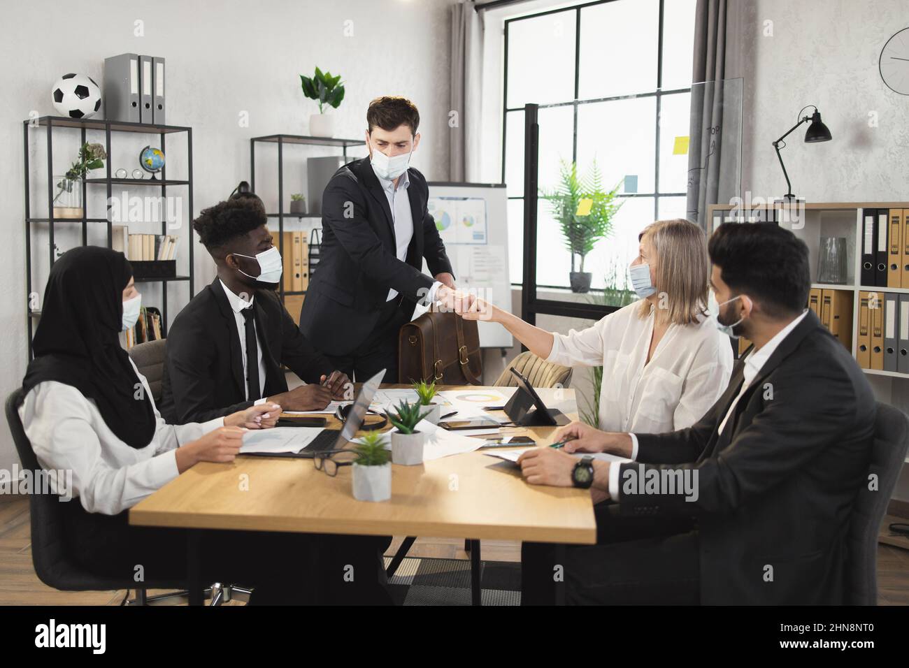 Multiracial business people in face masks greeting with fists during ...