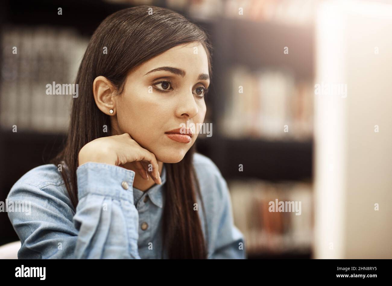 Focused on her bright and successful future. Shot of a university student working on a computer in the library at campus. Stock Photo
