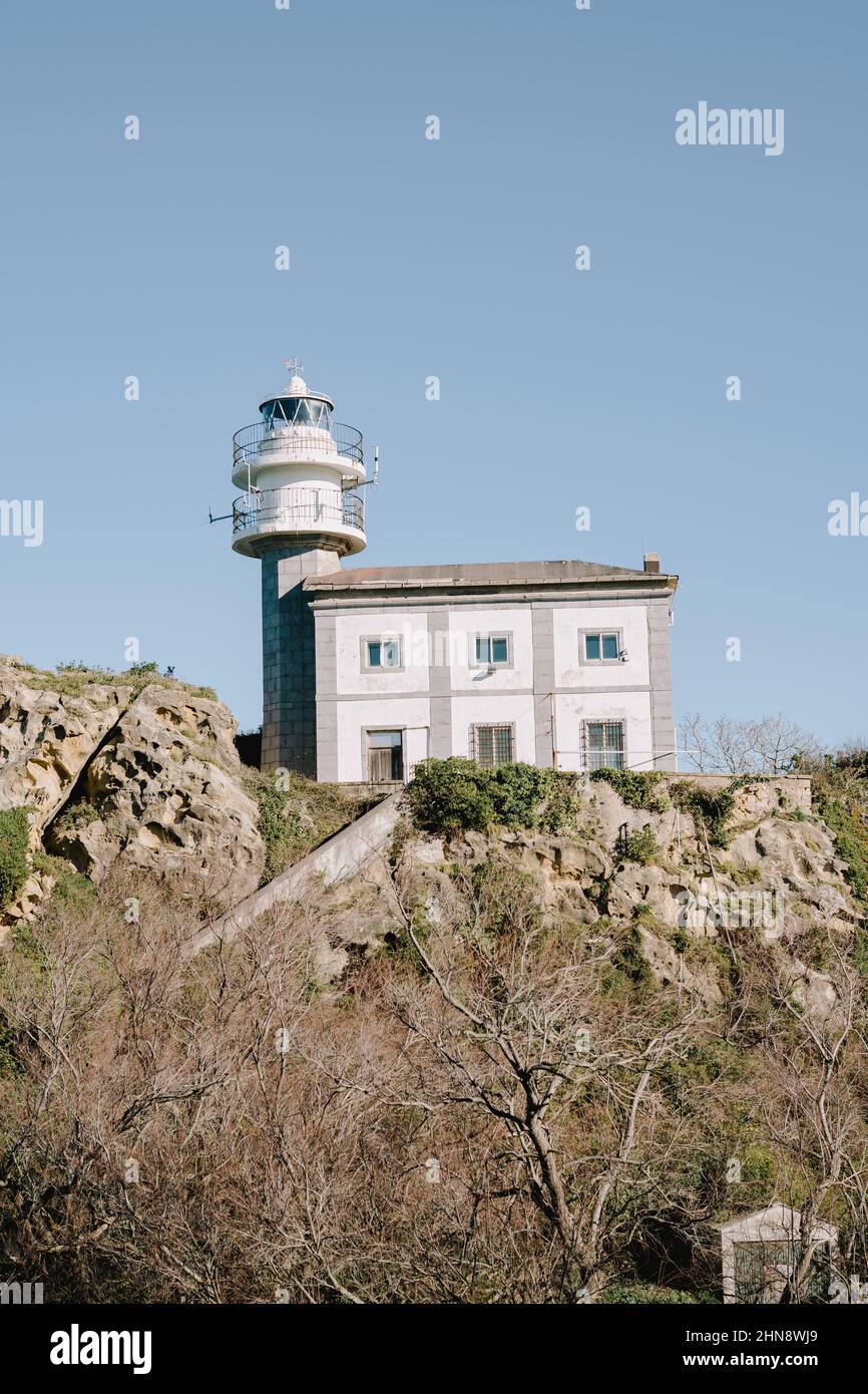 Vertical shot of a lighthouse next to a building in the daytime. Stock Photo