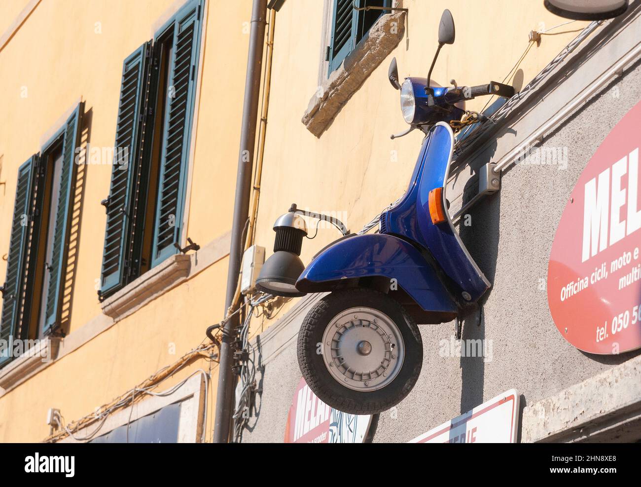 Pisa, Italy - March 29, 2021 - Vespa Piaggio cut in half and hung outside a workshop as a sign Stock Photo