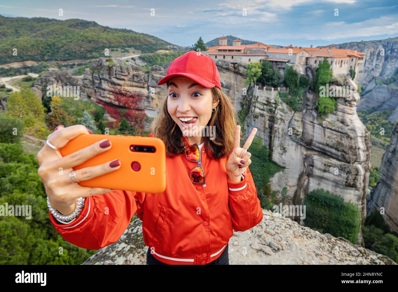 Happy traveler girl taking selfie photos while standing on top of a
