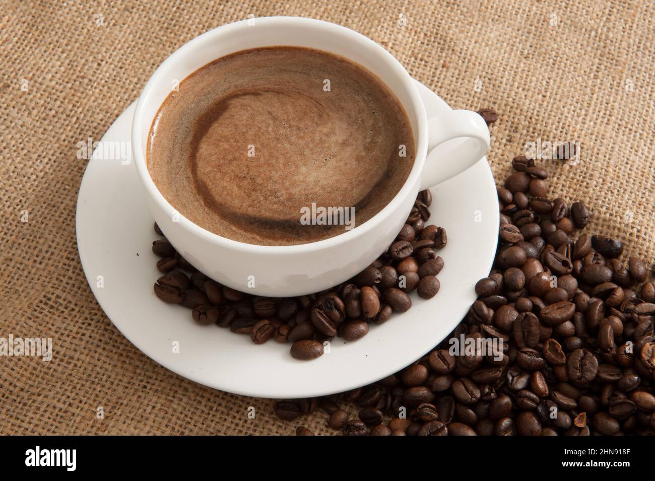Cup with coffee and coffee beans and steam over cup on burlap background Stock Photo