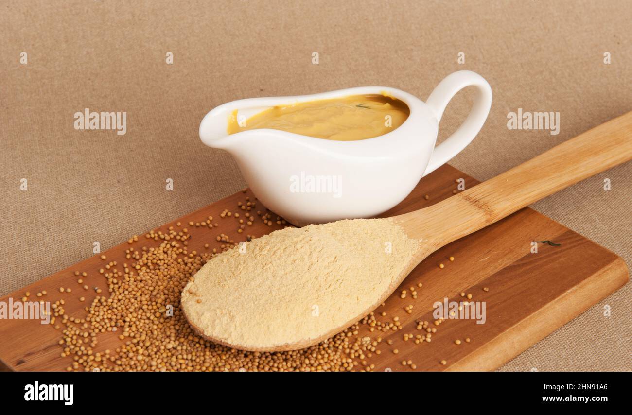Mustard in a gravy boat and mustard seeds Stock Photo