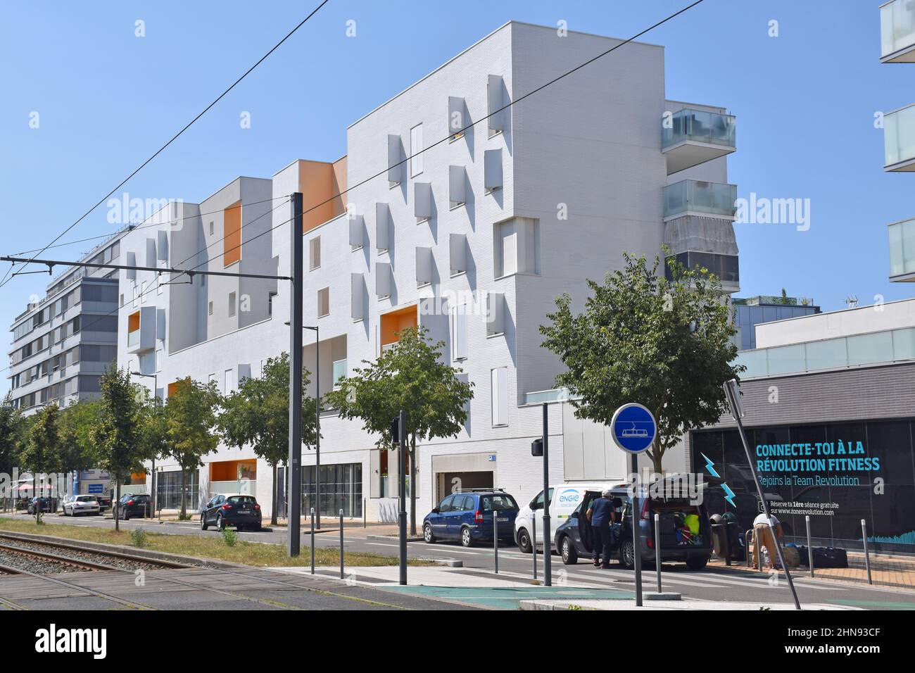 A six storey apartment building, clad in white ceramic tiles, with white shutters, some set backs, projecting balconies creating a Mediterranean feel Stock Photo