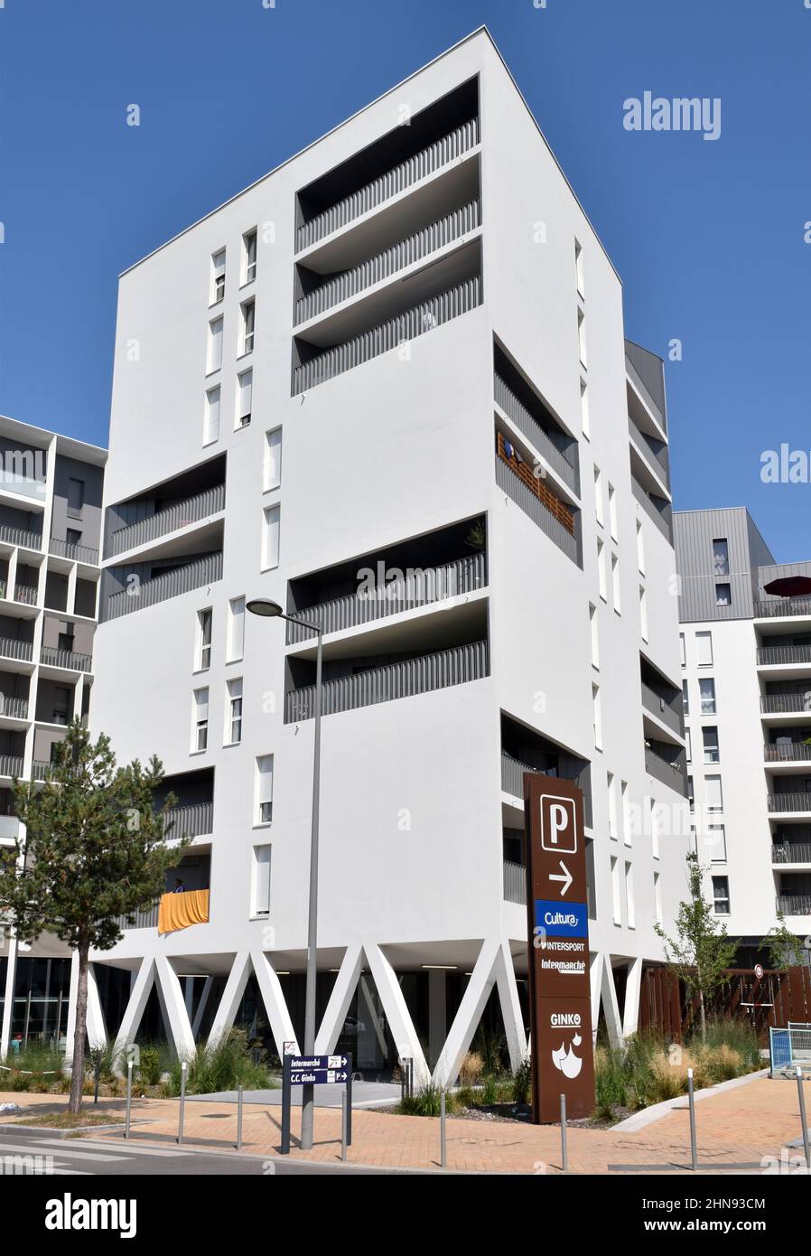 A six storey apartment building, clad in white ceramic tiles, white shutters and some set backs and projecting balconies creating a Mediterranean feel Stock Photo
