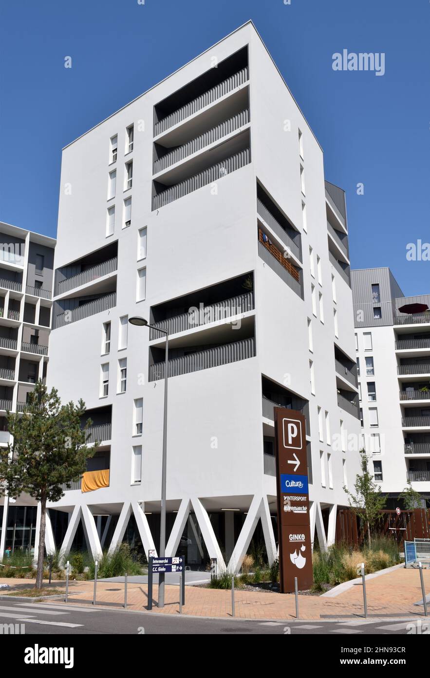 A six storey apartment building, clad in white ceramic tiles, white shutters and some set backs and projecting balconies creating a Mediterranean feel Stock Photo