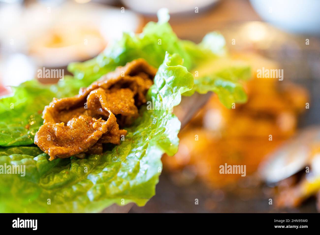 Close up of ssam Korean BBQ, pan-fried black pork with lettuce meal in Korea restaurant, fresh delicious korean cuisine. Stock Photo