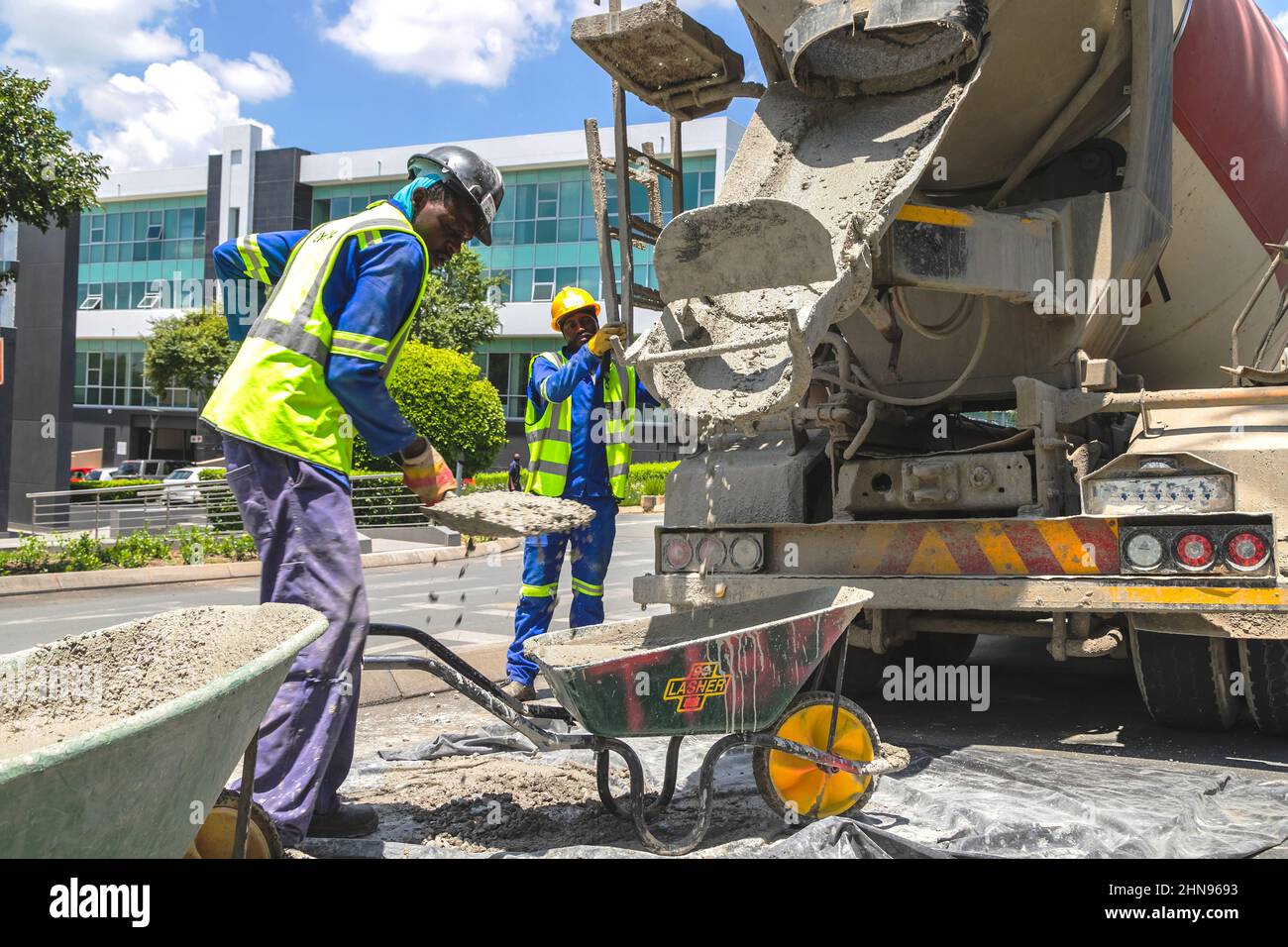 Johannesburg, South Africa, 3rd February - 2022: Construction worker shovelling cement into wheelbarrow. Stock Photo