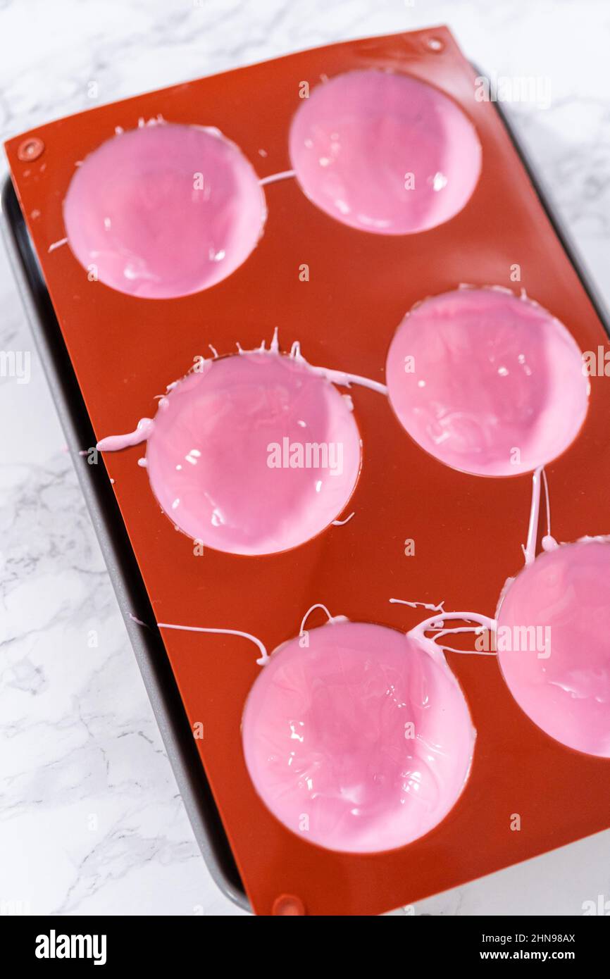 Filling in silicone chocolate molds with melted pink chocolate to
