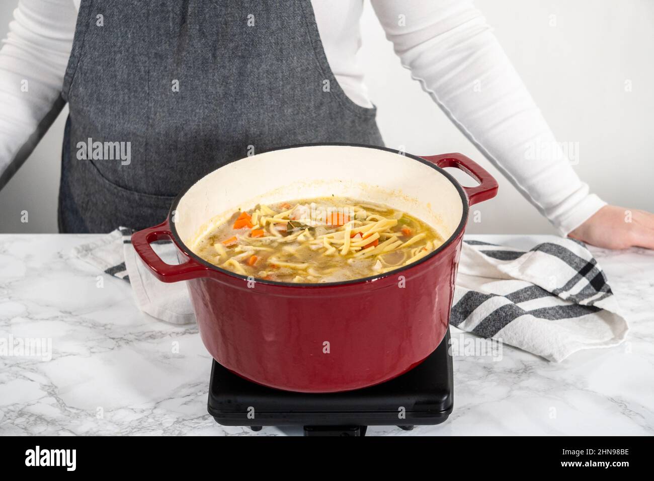Cooking chicken noodle soup with kluski noodles in an enameled dutch