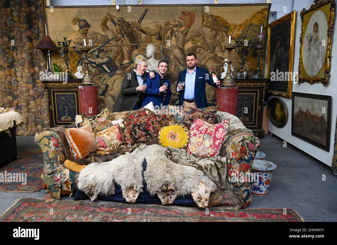 Billingshurst , Sussex,  UK 15th February 2022 - From left Sara Cooper , Adam Garner and Will Pasfield  from Bellmans Fine Art Auctioneers, Wisborough Green near Billingshurst with Uncle Monty's famous sofa which is amongst furniture going to auction next week . Items from the  home of Professor Bernard Nevill, whose Chelsea home was the location for Uncle Monty's flat in the film 'Withnail & I ' which celebrates its 35th anniversary this year will go for sale by auction next week on the 23rd February   : Credit Simon Dack / Alamy Live News Stock Photo