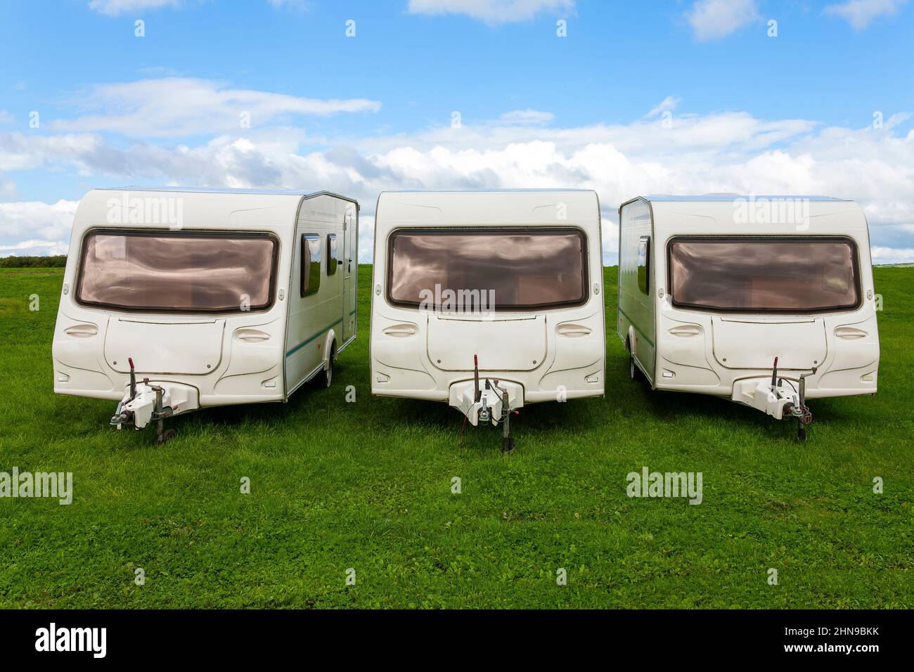 Caravan travel trailers used for outdoor camping which are parked up in a green grass campsite park field where a family can enjoy a fun vacation at t Stock Photo