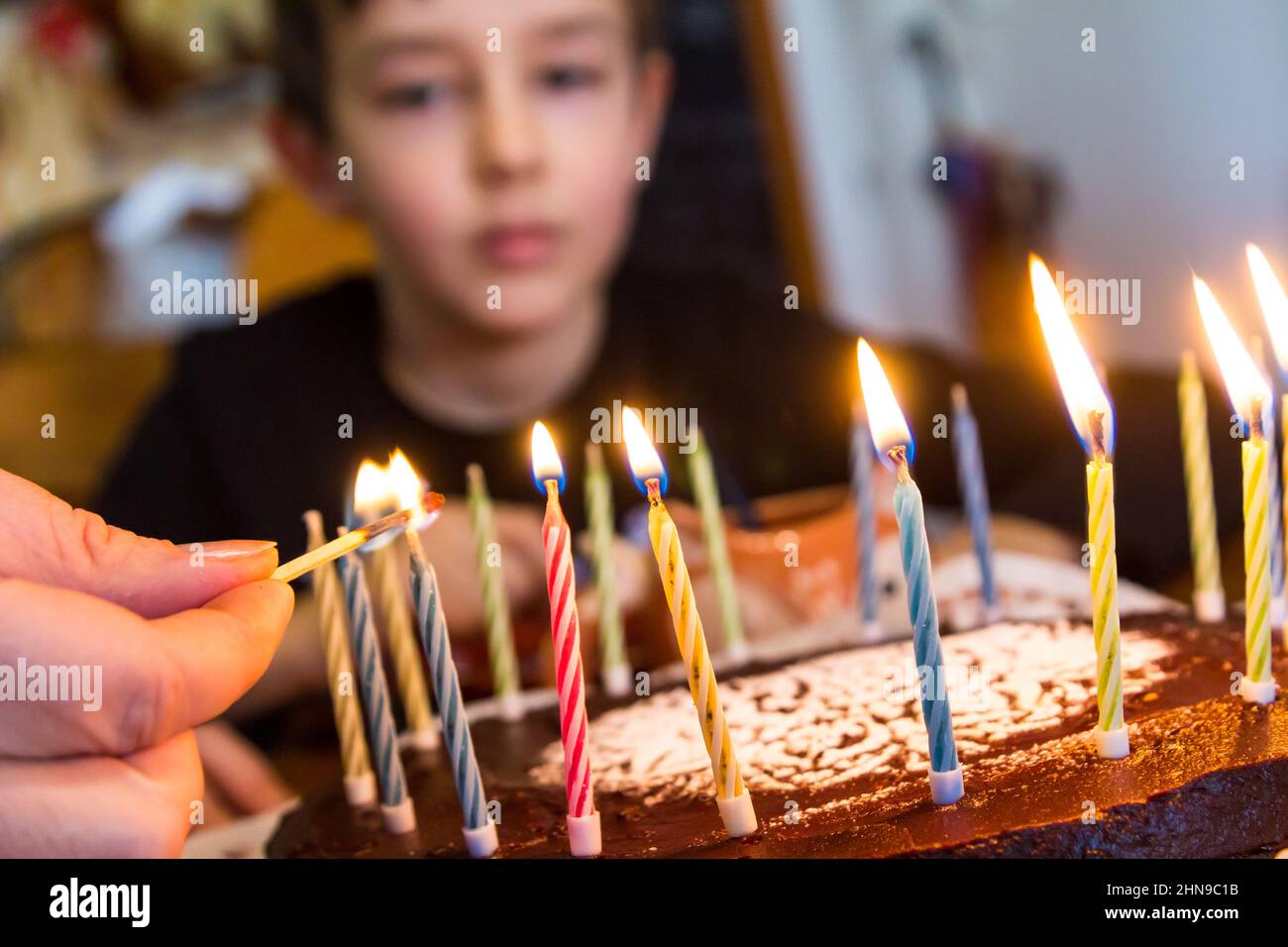 Lighting trick birthday candles with a match, boy's face blurred in the