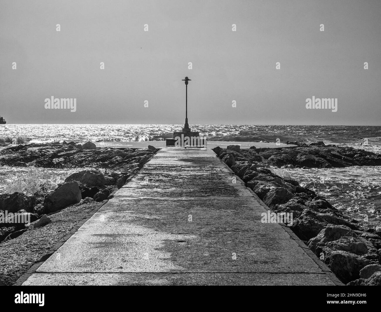 Streetlight on the tip of a breakwater facing the sea Stock Photo