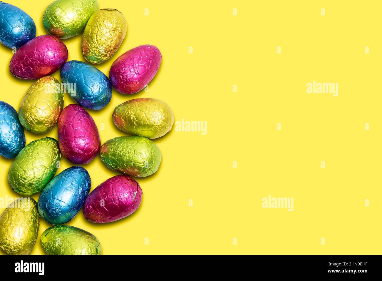 Colorful wrapped Easter eggs on yellow background. Stock Photo