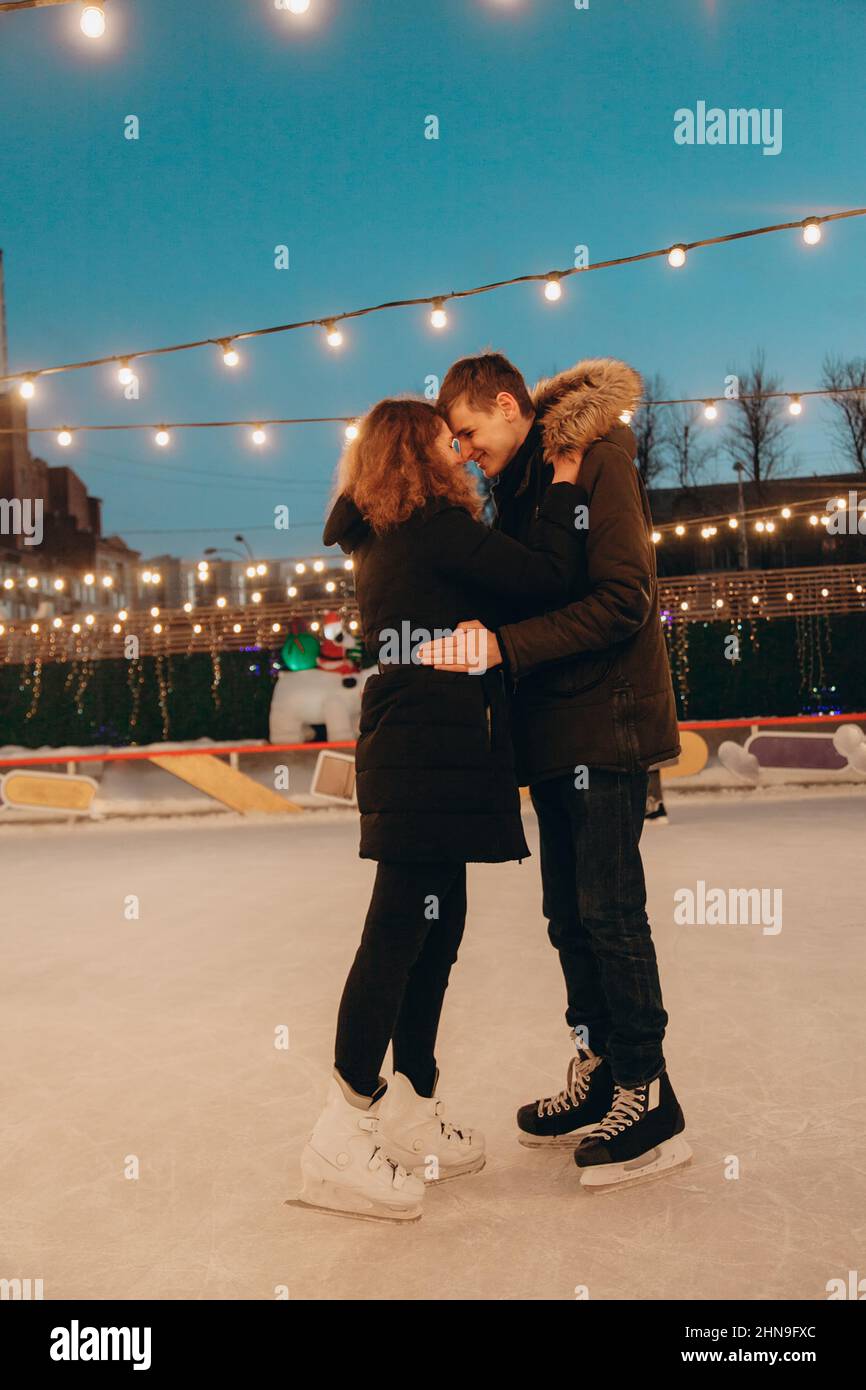 A young couple in love is skating on a skating rink, hugging and smiling. Stock Photo