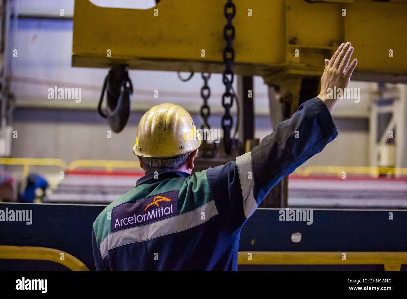 Temirtau, Kazakhstan - June 08, 2012: Arcelor Mittal metallurgy plant.Worker  with conveyor belt and crane with lifting magnet WOKO for square bar met Stock Photo
