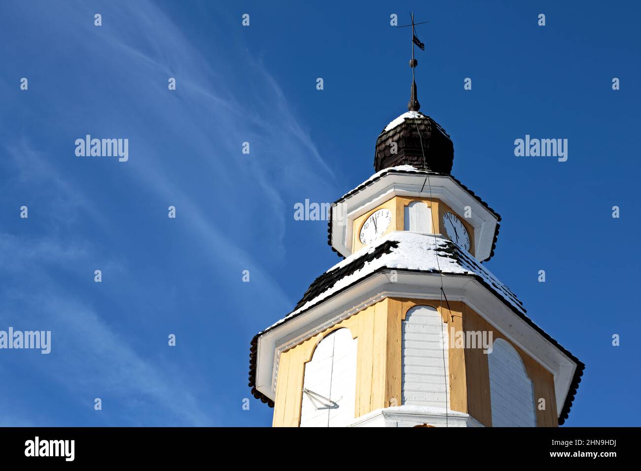 A yellow clock tower of an old church with blue sky and white thin cloud on a background Stock Photo