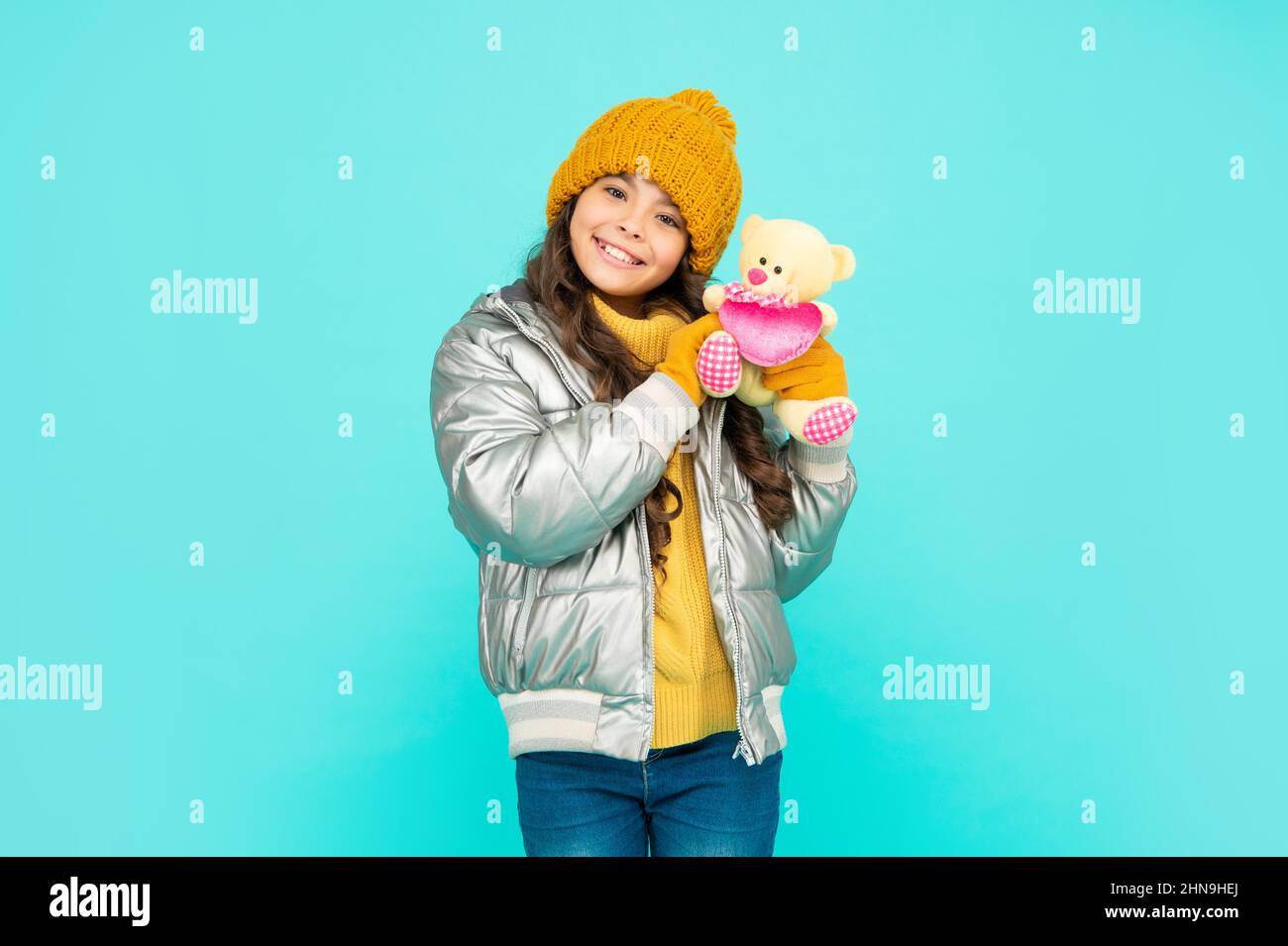 cheerful kid in hat and gloves hold toy on blue background, valentines day Stock Photo
