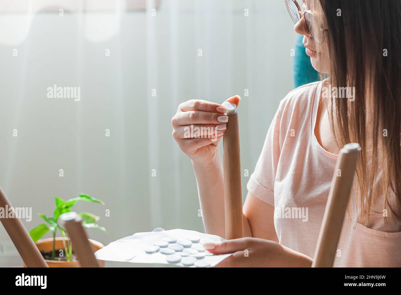 Woman attach felt pad on chair leg, care of floor Stock Photo Alamy