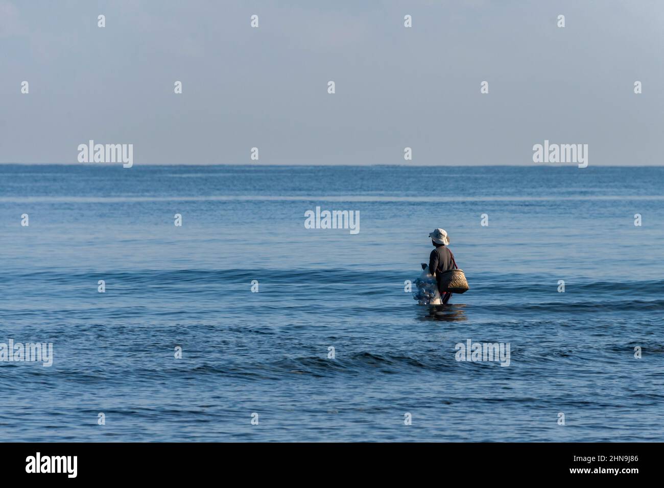 Man walking on the sea holding fishing net Stock Photo