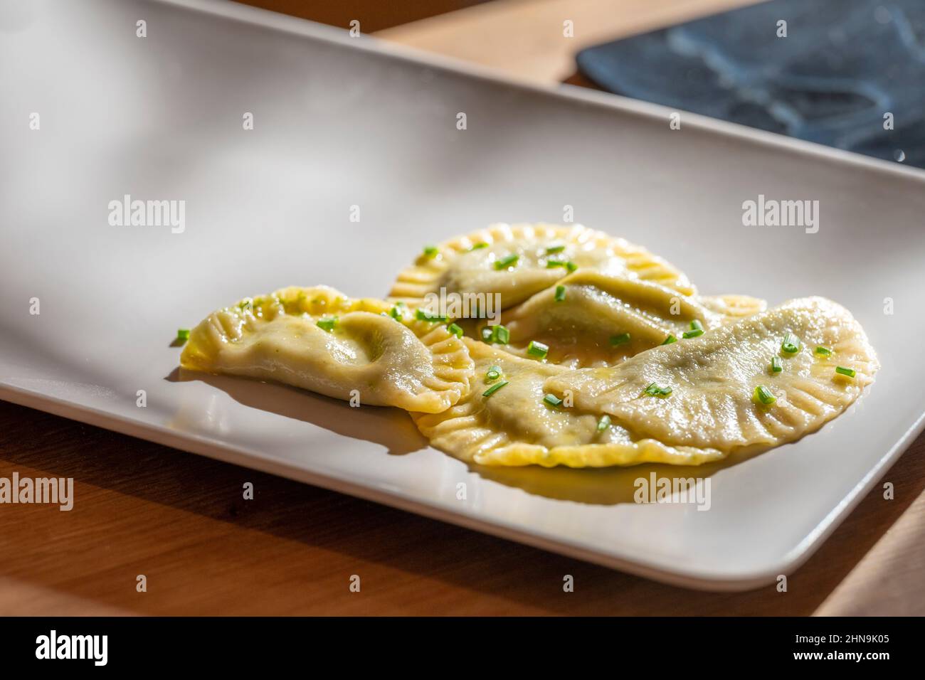 homemade tyrolean dumplings with spinach filling served on a white plate with chives Stock Photo