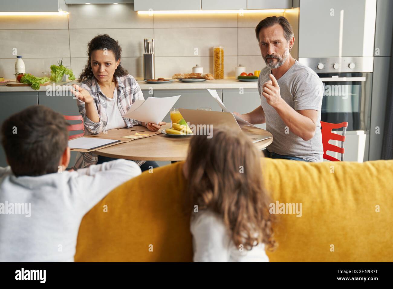 Strict parents reprimanding their kids on sofa Stock Photo