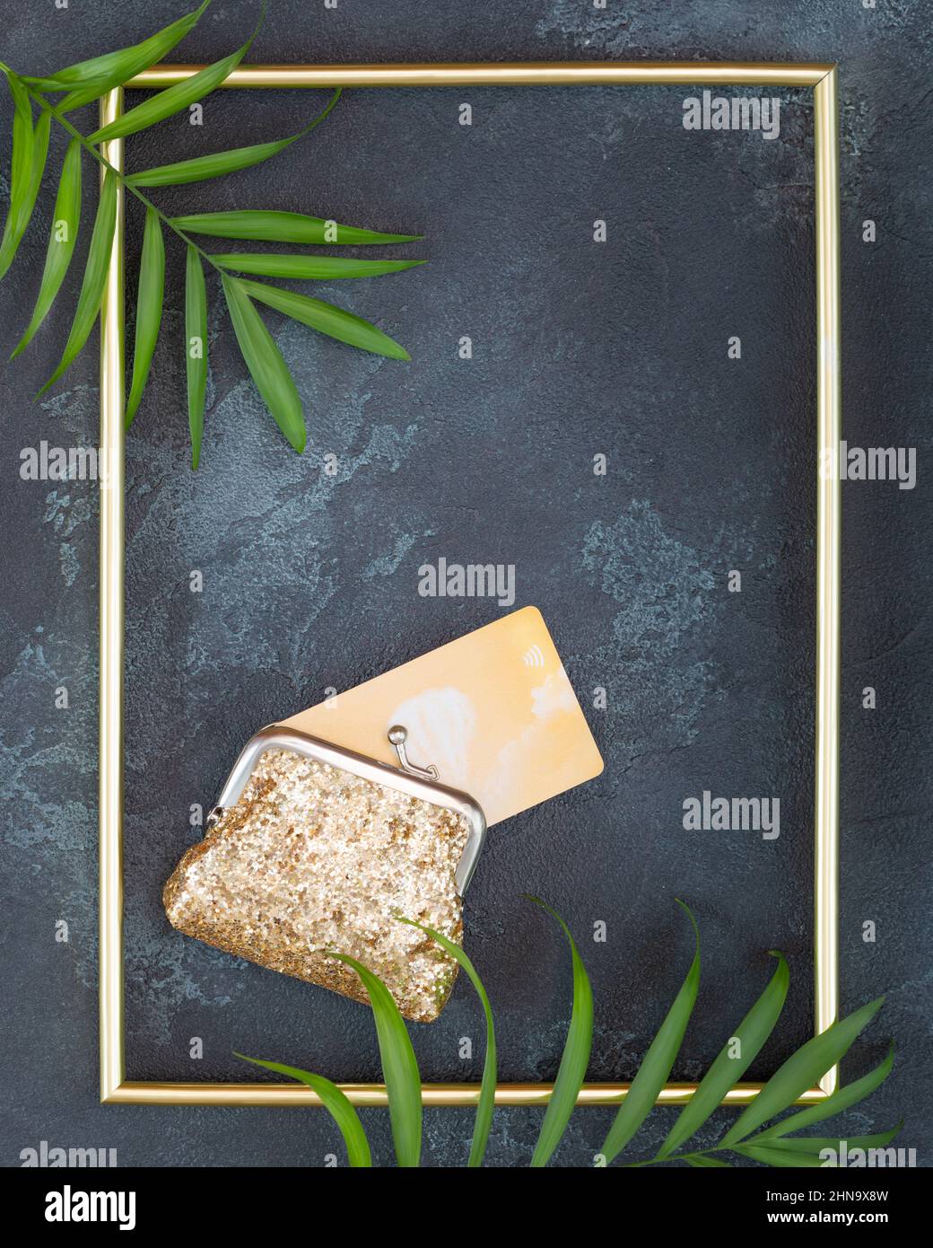 Gold wallet with gold credit card and gold frame on a black textured