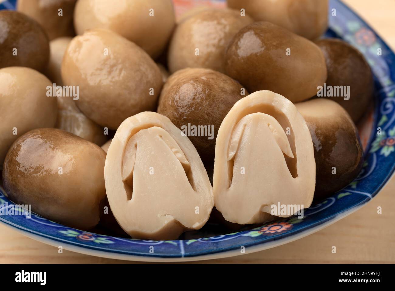 Whole and half canned straw mushroom in a bowl close up Stock Photo