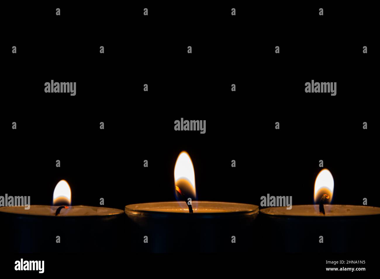Three burning tea lights on a black background Stock Photo Alamy