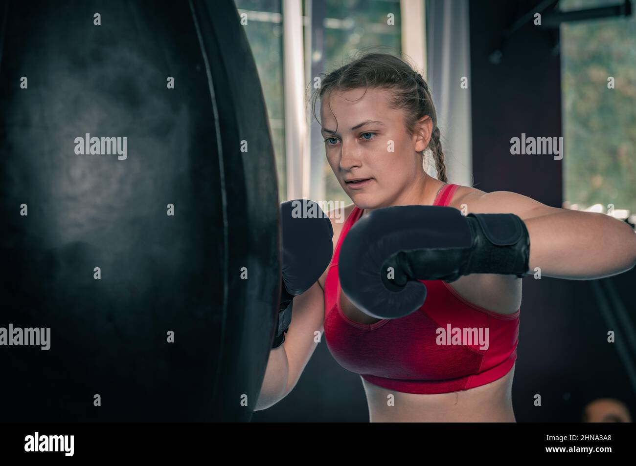 Woman boxing with punching bag in garage gym Stock Photo Alamy