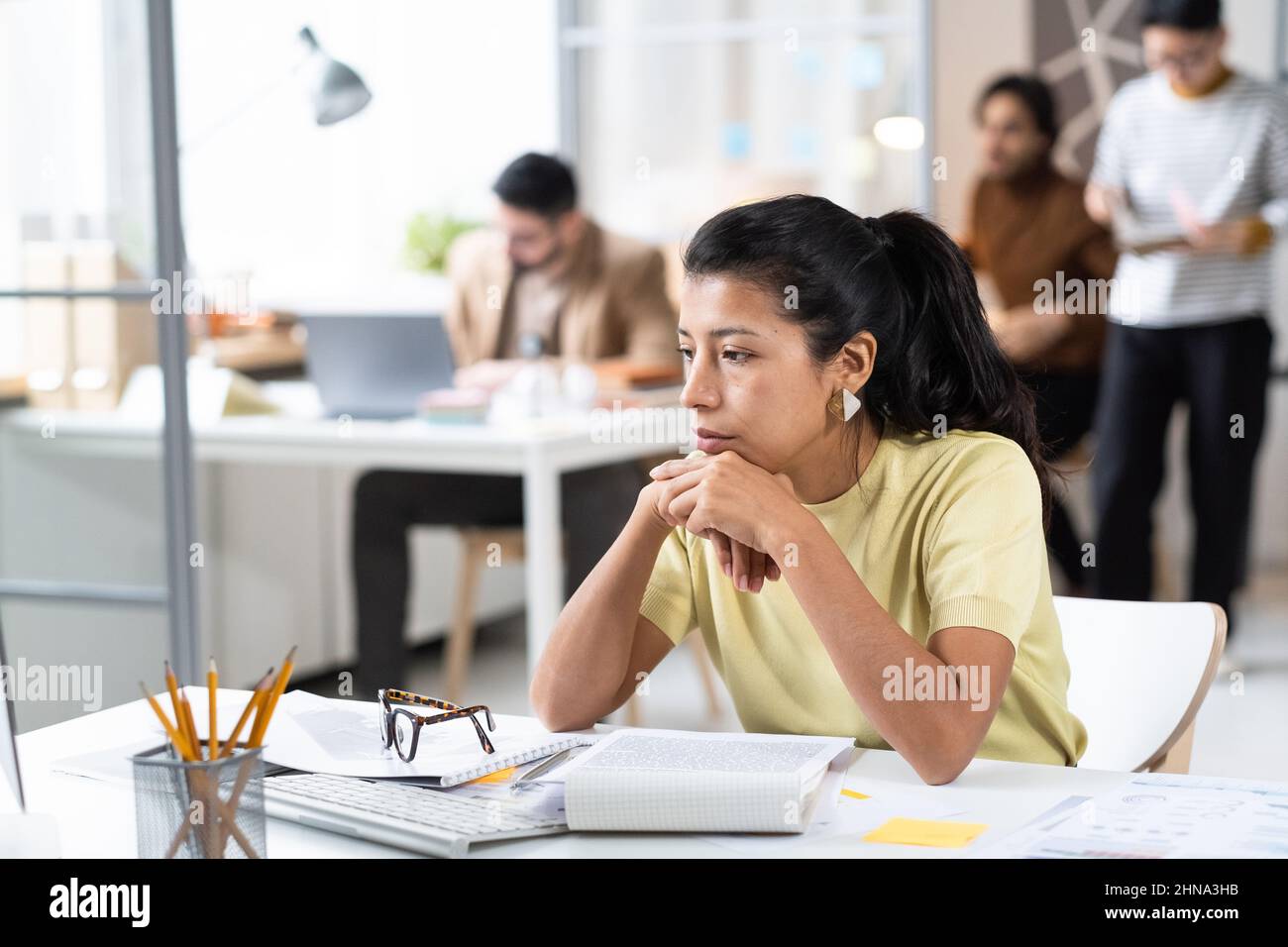 Serious businesswoman sitting at her workplace with documents with pensive expression, she working hard at office Stock Photo