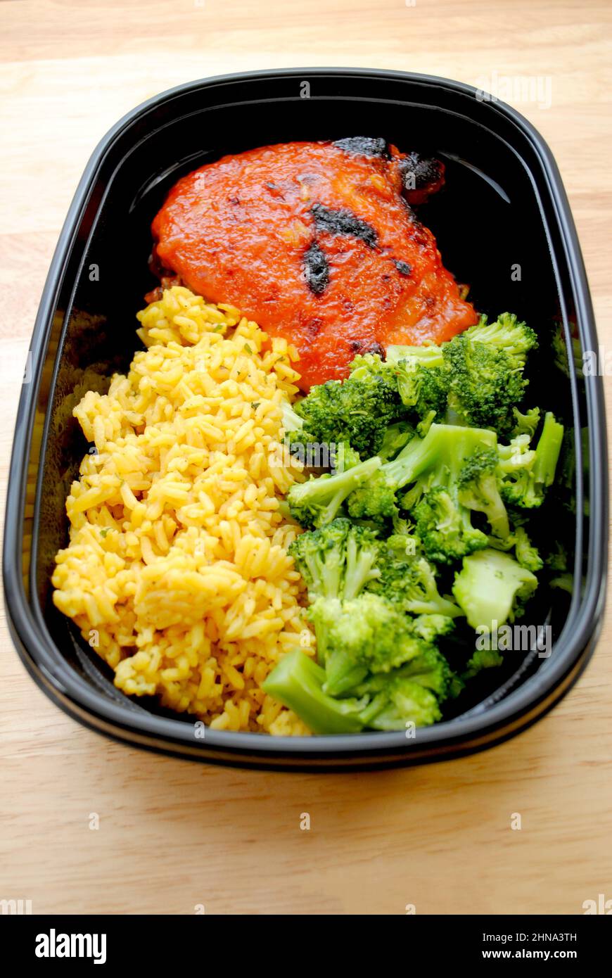 A Meal of a Chicken Thigh with Catalina Dressing Baked on Top, Yellow Rice and Steamed Broccoli Stock Photo