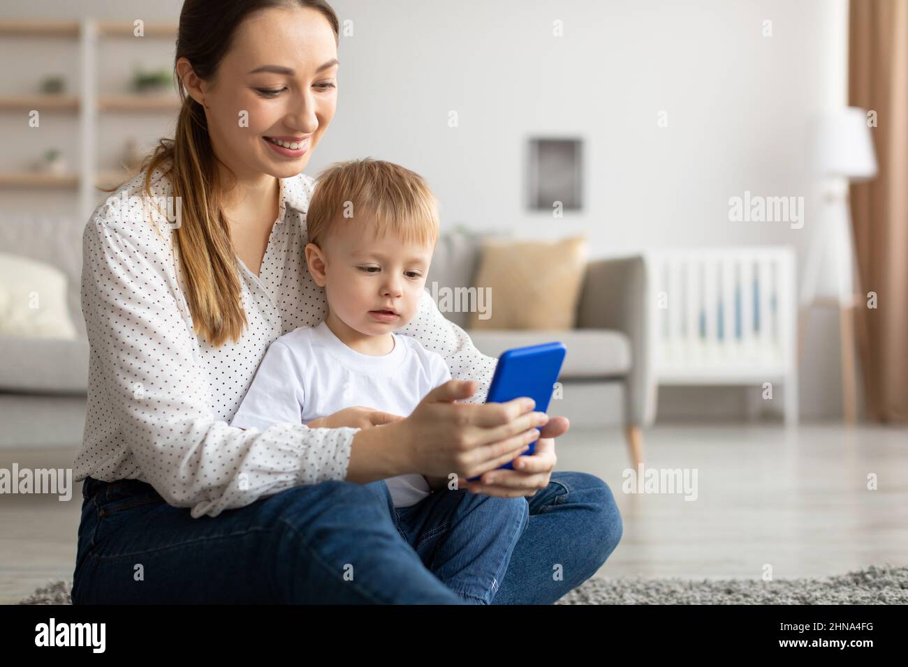 Kids and technologies. Happy mom and her son using smartphone, browsing ...