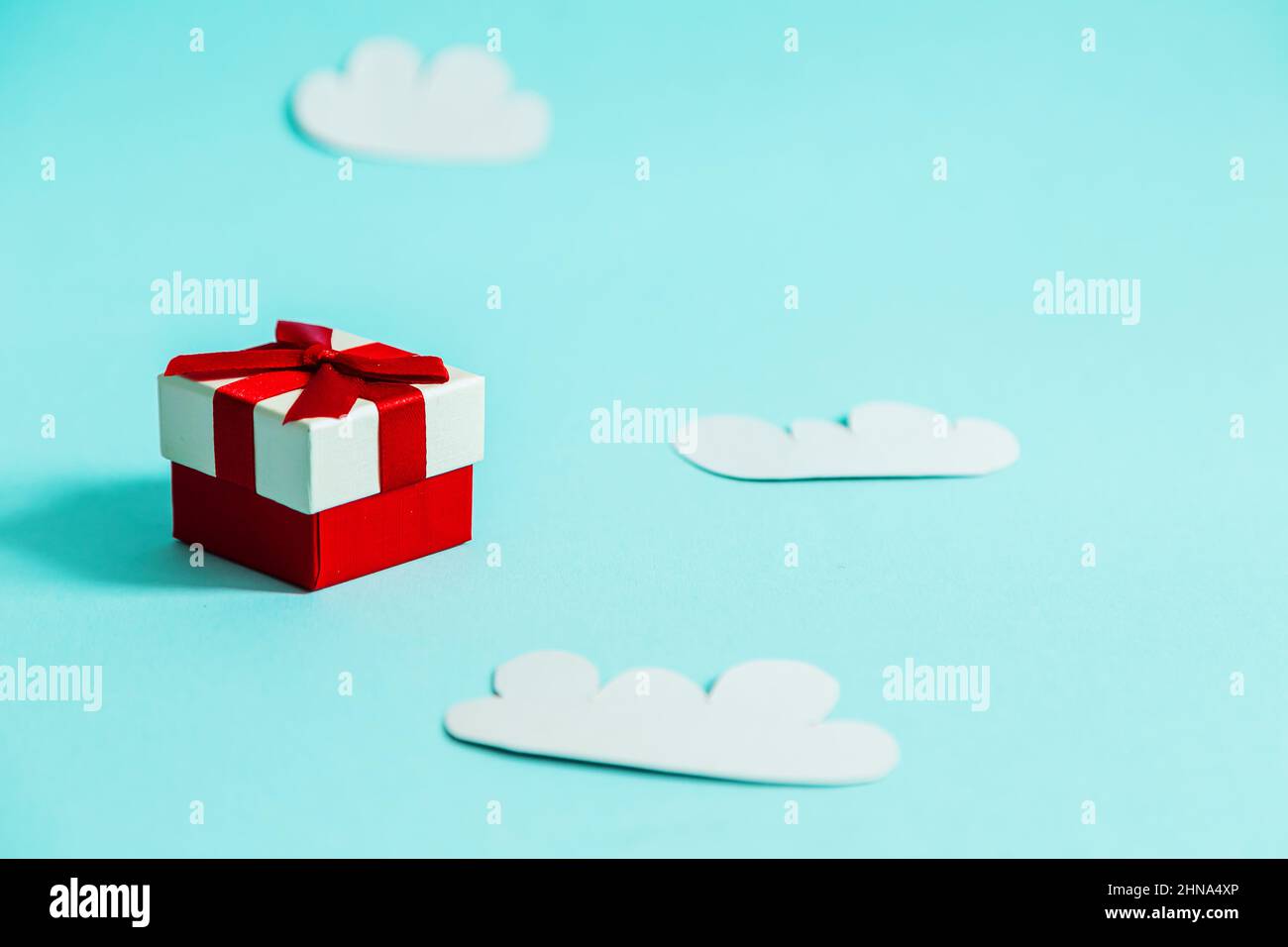 Gift box and paper clouds on a blue background. Stock Photo