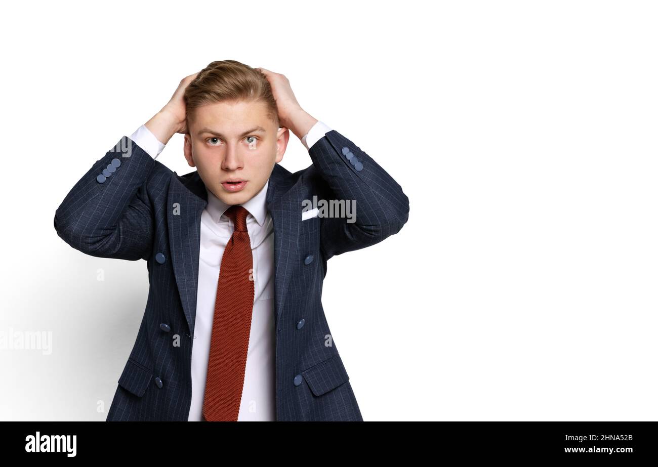 Sad young businessman, student, diplomat holding hands on head isolated on white studio background. Human emotions, facial expression concept. Stock Photo