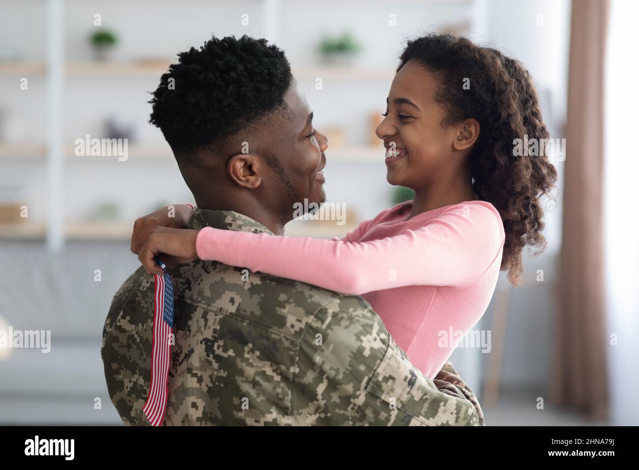 Cheerful girl with flag of the US hugging her dad Stock Photo
