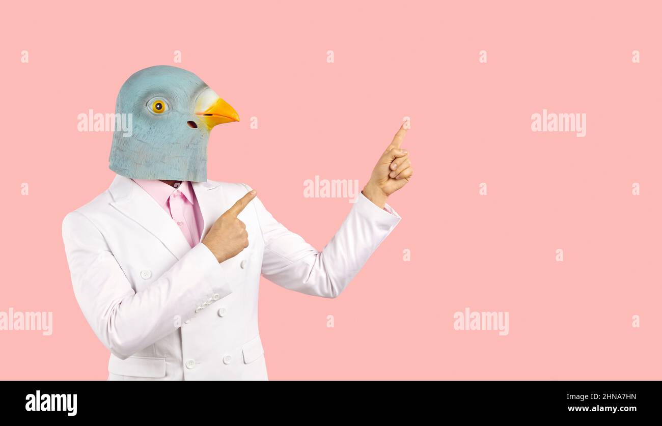 Funny guy in suit and pigeon mask pointing fingers away at pink copy