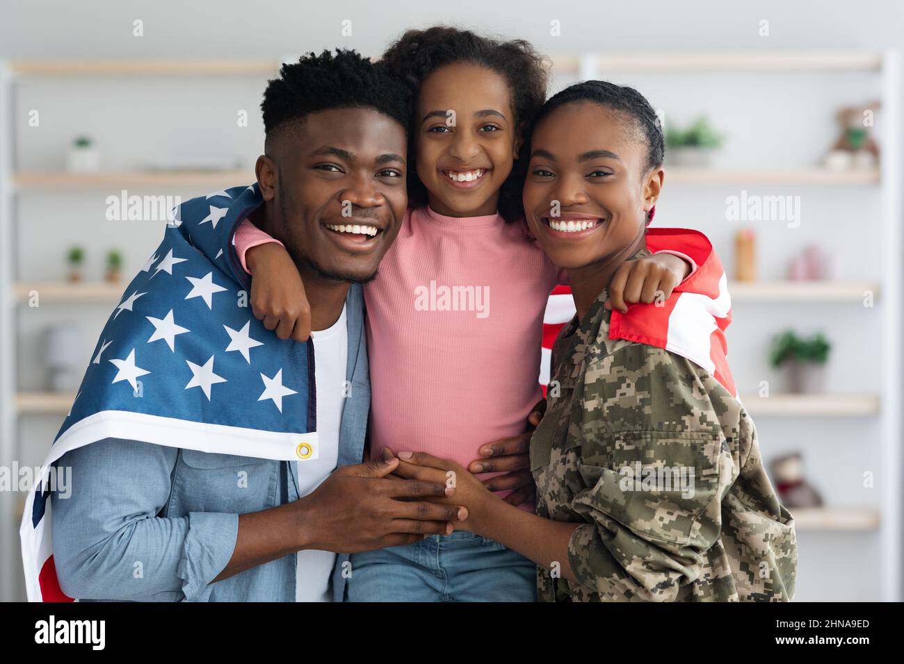 Cheerful girl with flag of US hugging her parents Stock Photo