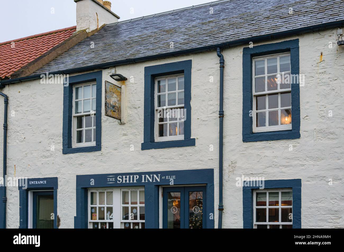 The Ship Inn in Elie village on the coast of Fife, Scotland, overlooking the Firth of Forth. Woman looking from window across the harbour beach. Stock Photo