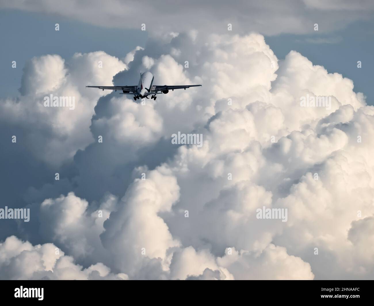 A Jet Airliner flies into the clouds Stock Photo