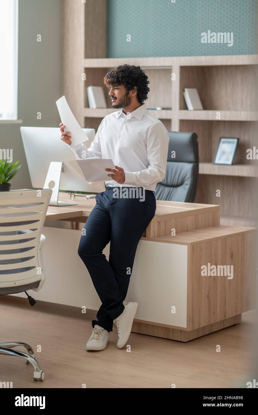 Young curly-haired manager feeling busy at work Stock Photo