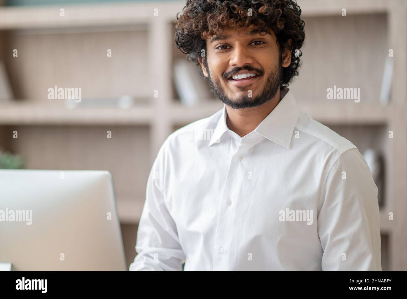 Young curly-haired manager feeling busy at work Stock Photo