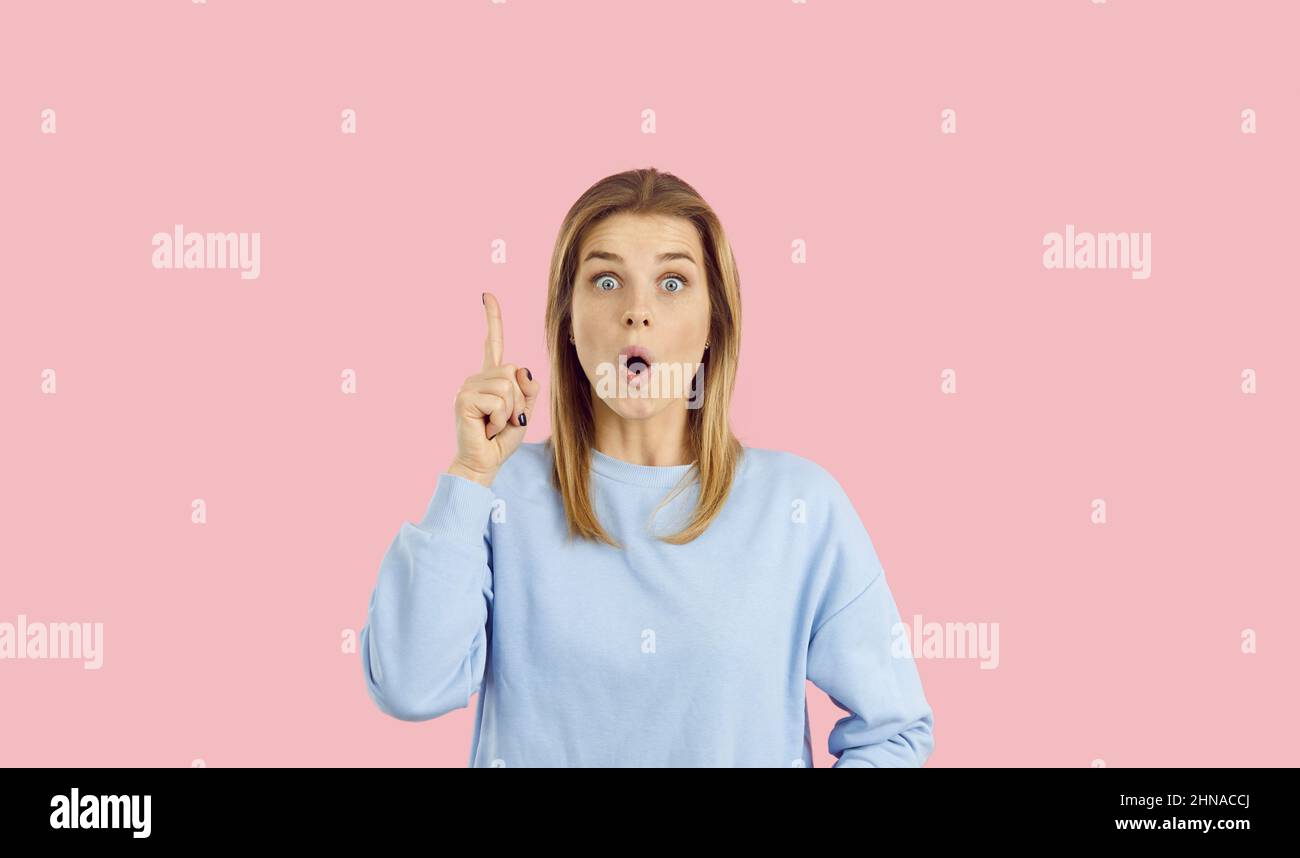 Funny girl having an aha moment and pointing her finger up with a surprised face expression Stock Photo